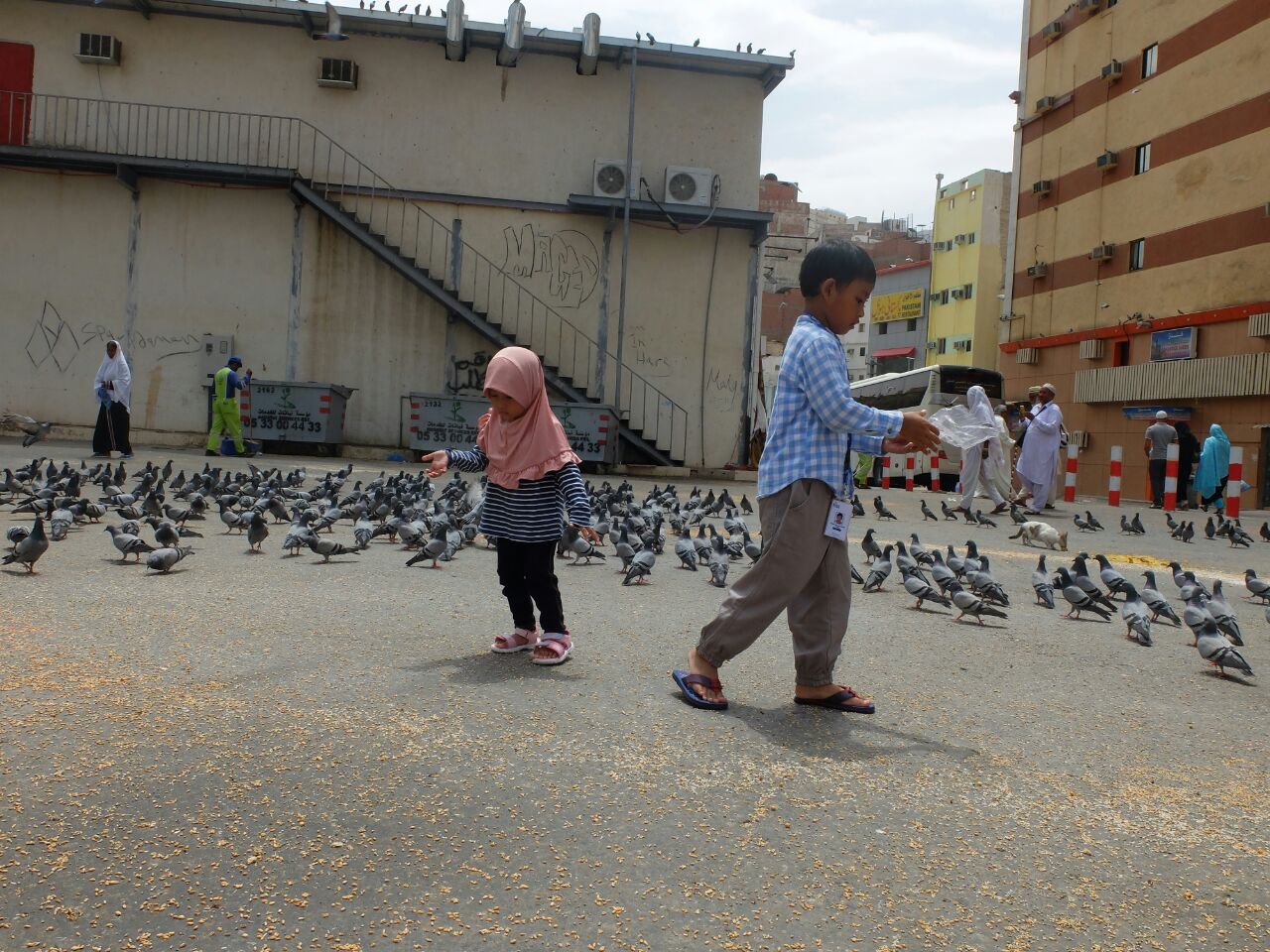 Anak-anak memberi makan burung di sebuah halaman dekat Masjidil Haram